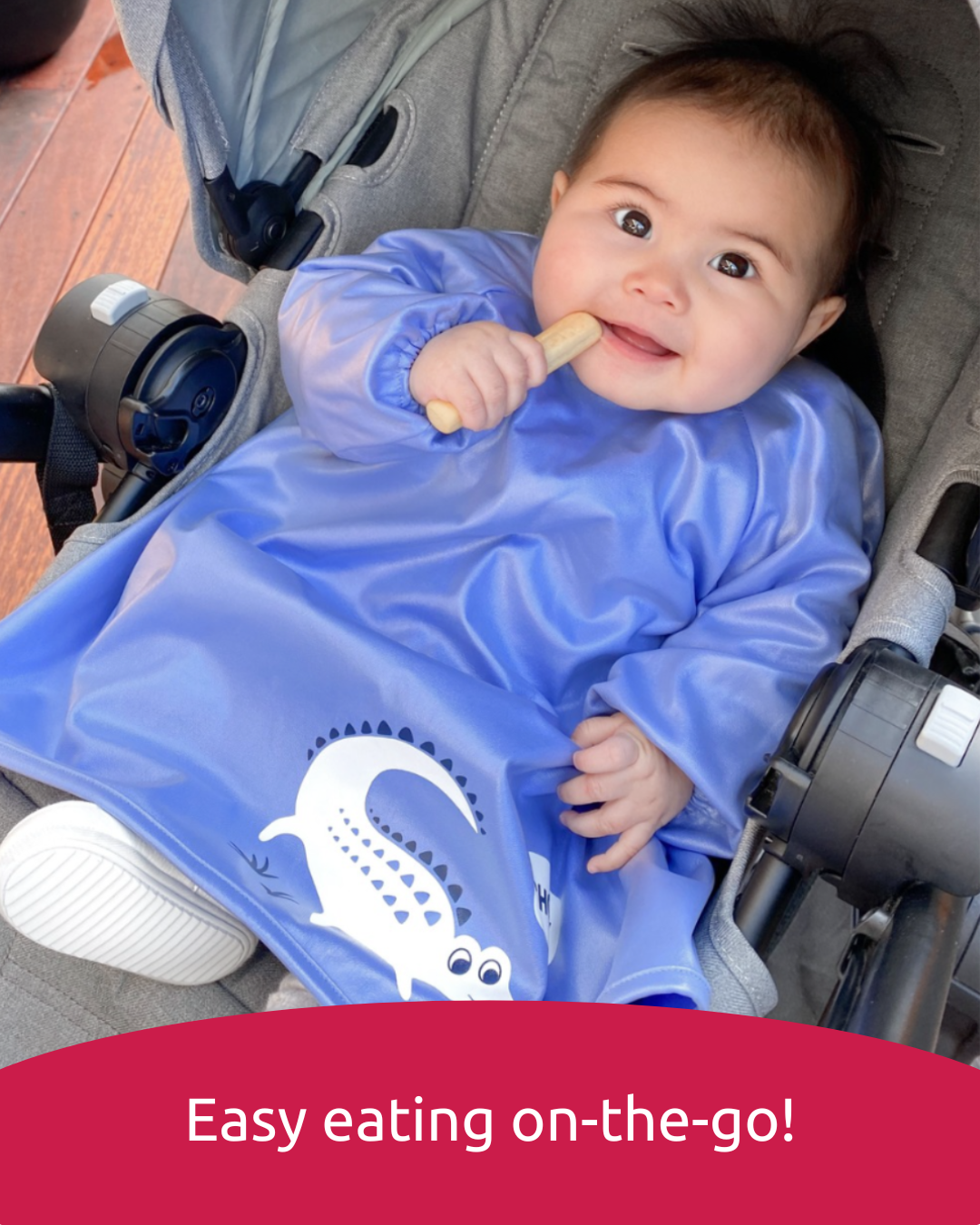 Baby wearing a blue feeding bib sitting in a pram or stroller.