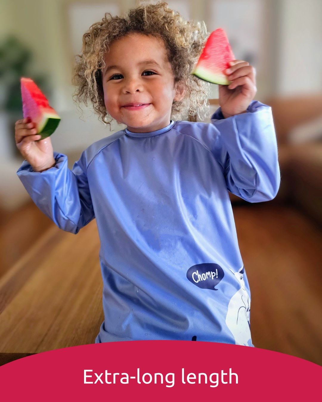 Boy wearing blue preschool smock bib eating watermelon.