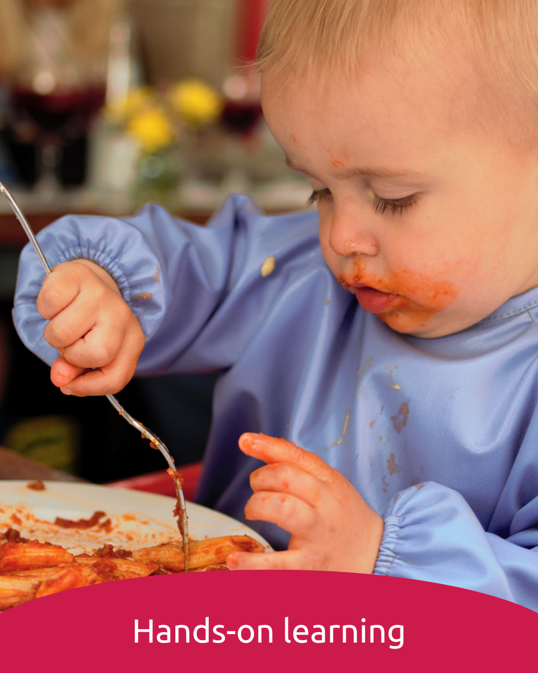 Toddler eating spaghetti wearing a feeding smock
