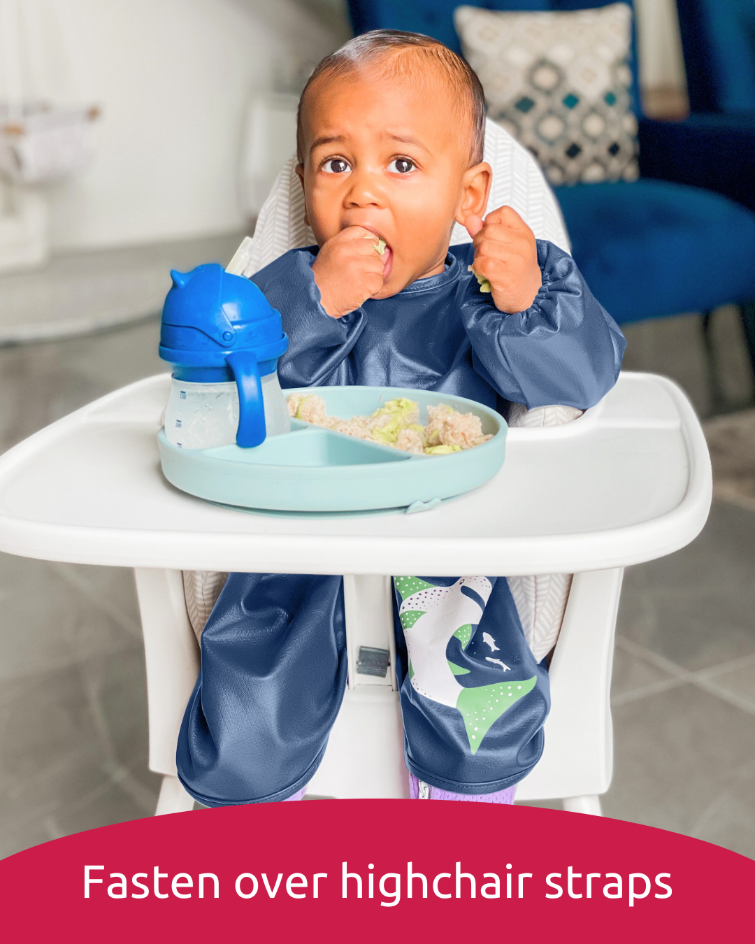 Baby wearing navy feeding smock weaning in highchair.