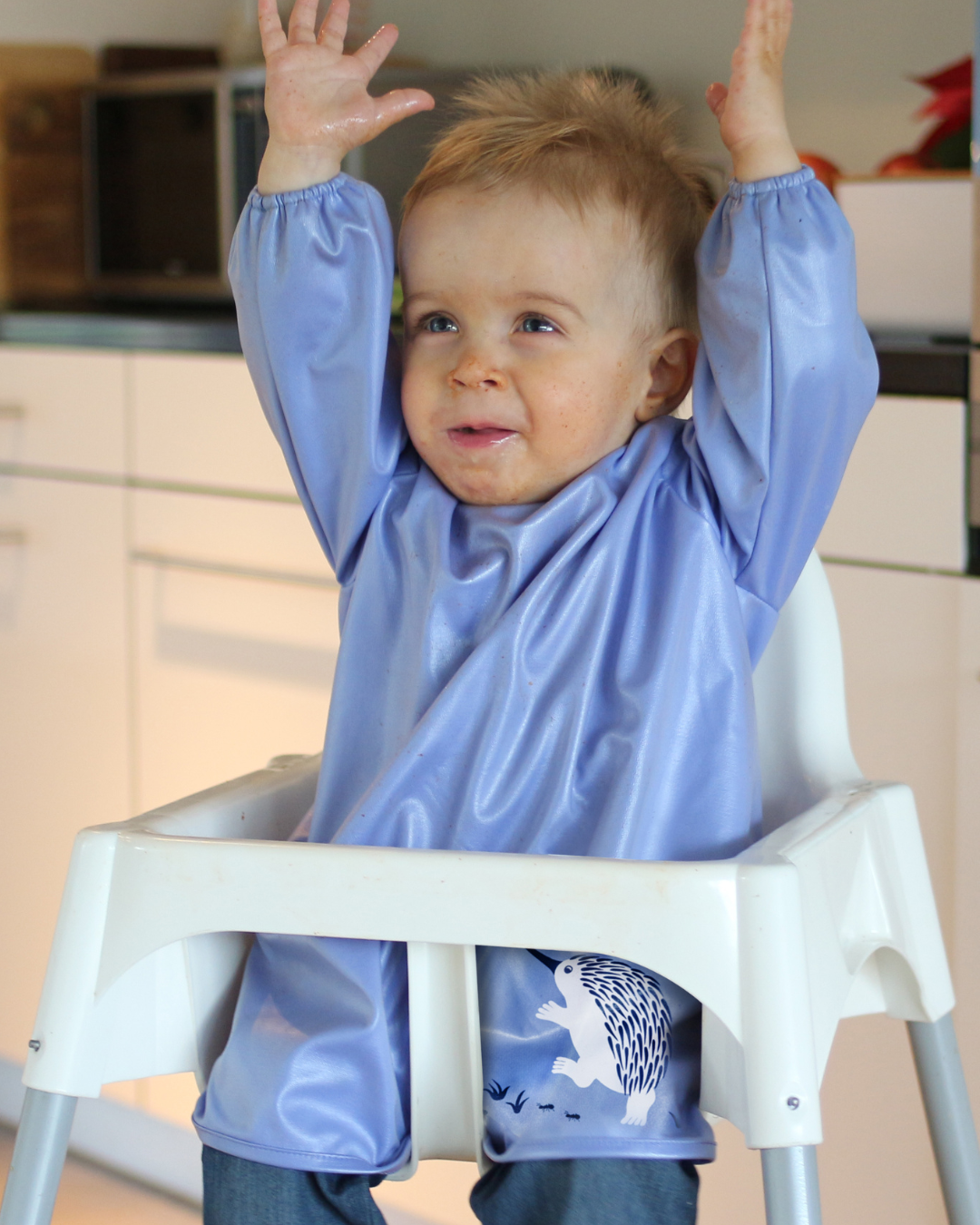 Toddler wearing a blue feeding smock.