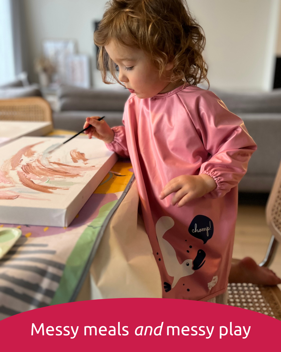 Toddler painting in pink childs smock.