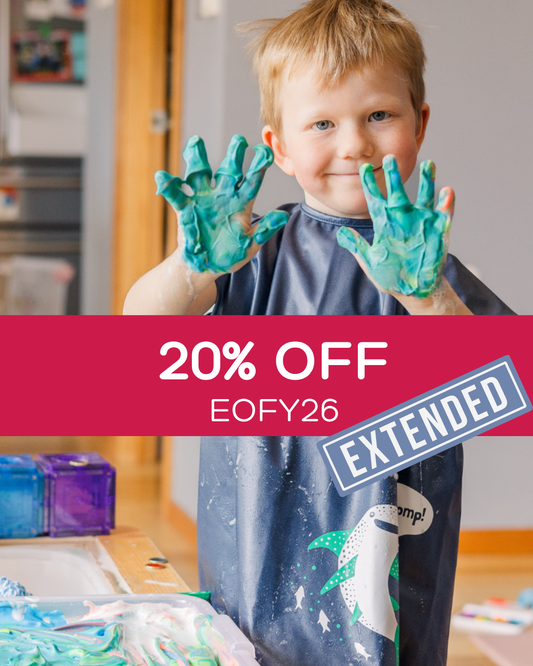 Child with green paint on hands playing in a short sleeved bib art smock.