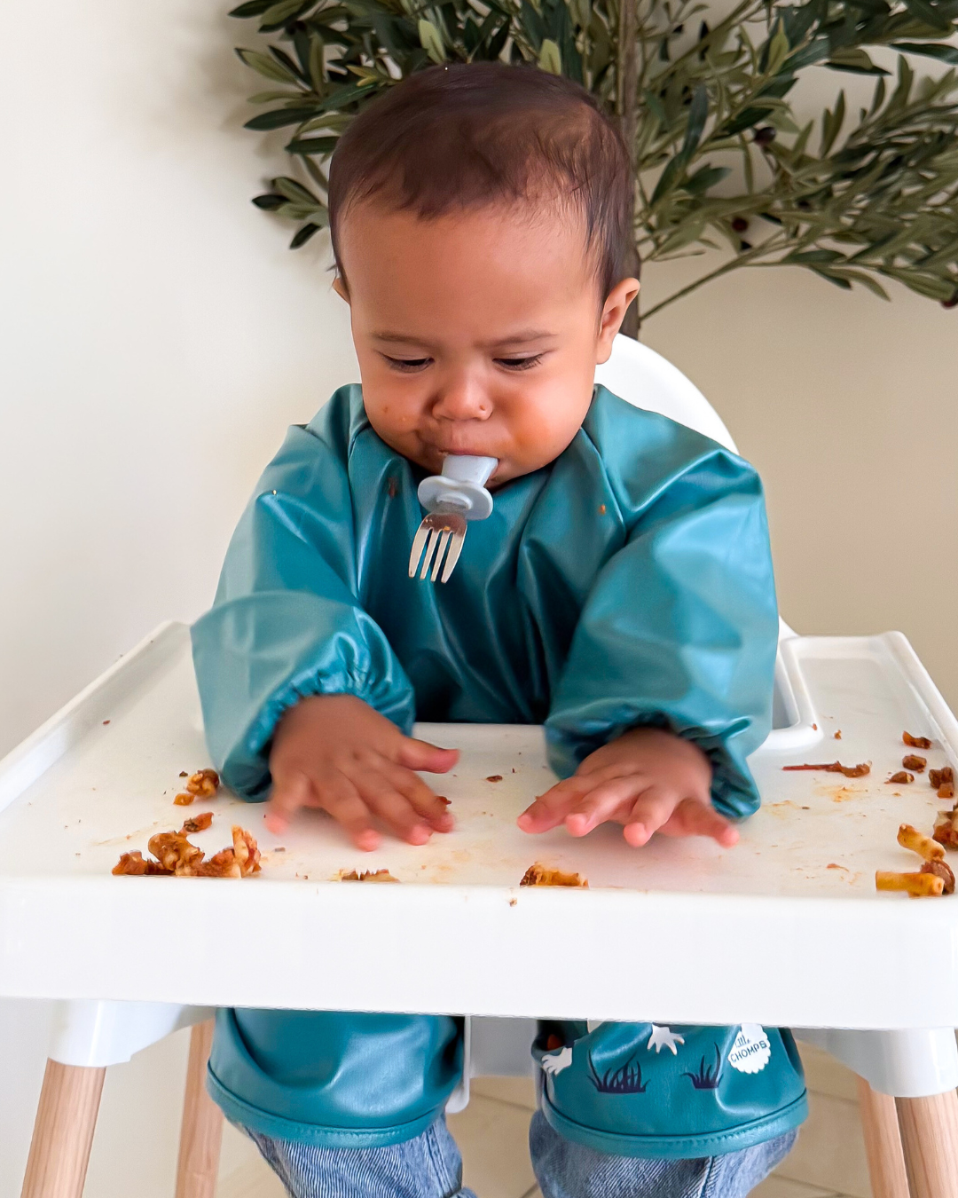 Baby led weaning in green feeding smock. 