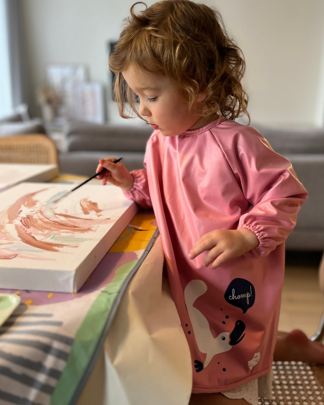 Toddler painting in pink child smock.