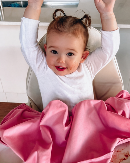 Child showing white tshirt under her pink feeding smock.