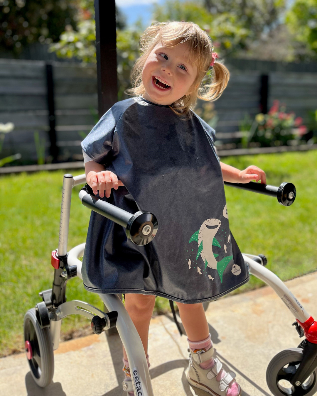 Girl wearing disability bib in mobility aid.