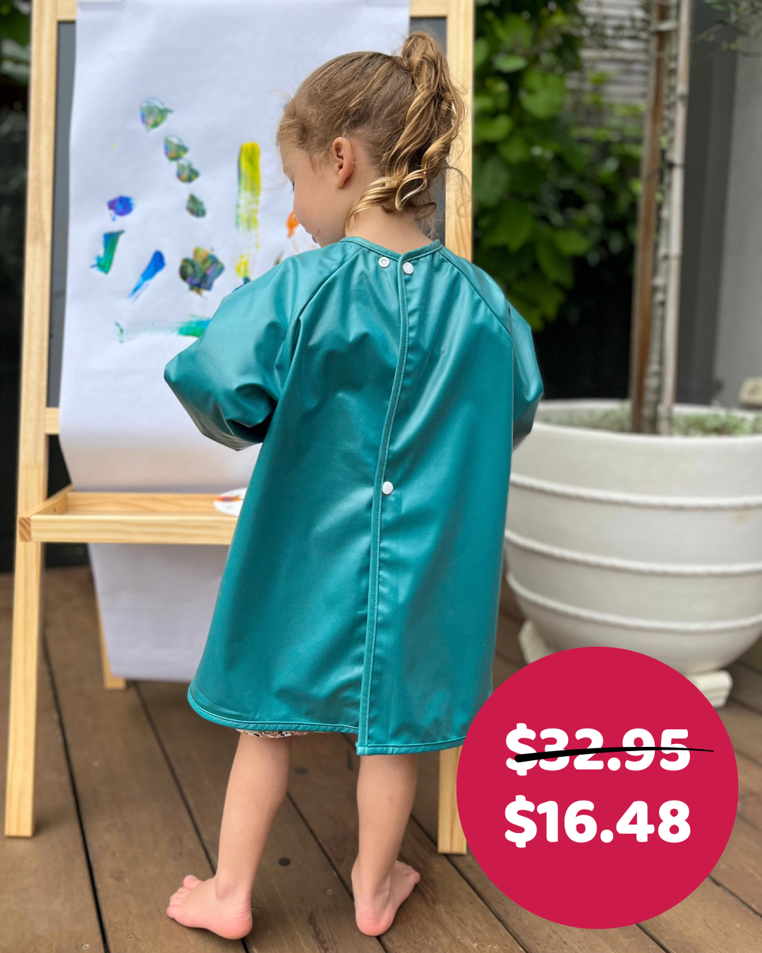 Child painting in green art smock.