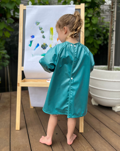 Girl painting wearing a green art smock.
