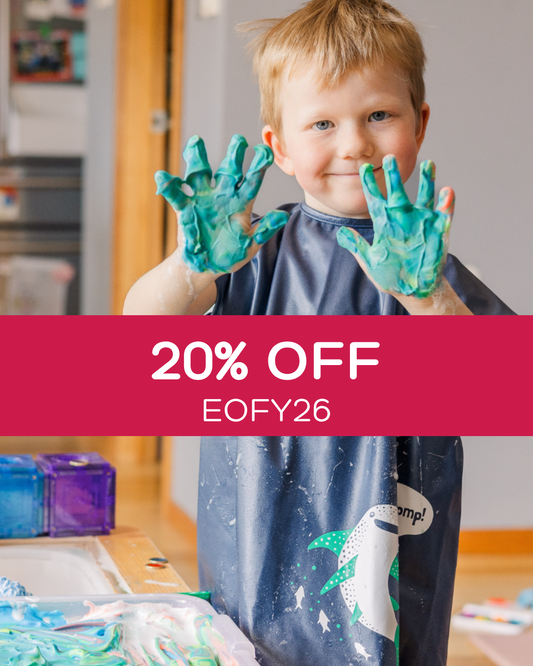 Child with green paint on hands playing in a short sleeved bib art smock.