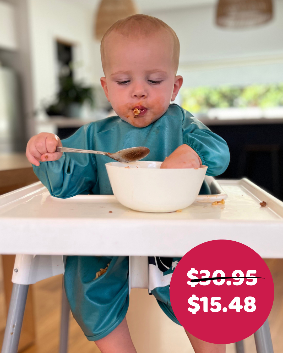 Boy eating with his hands in green smock bib.