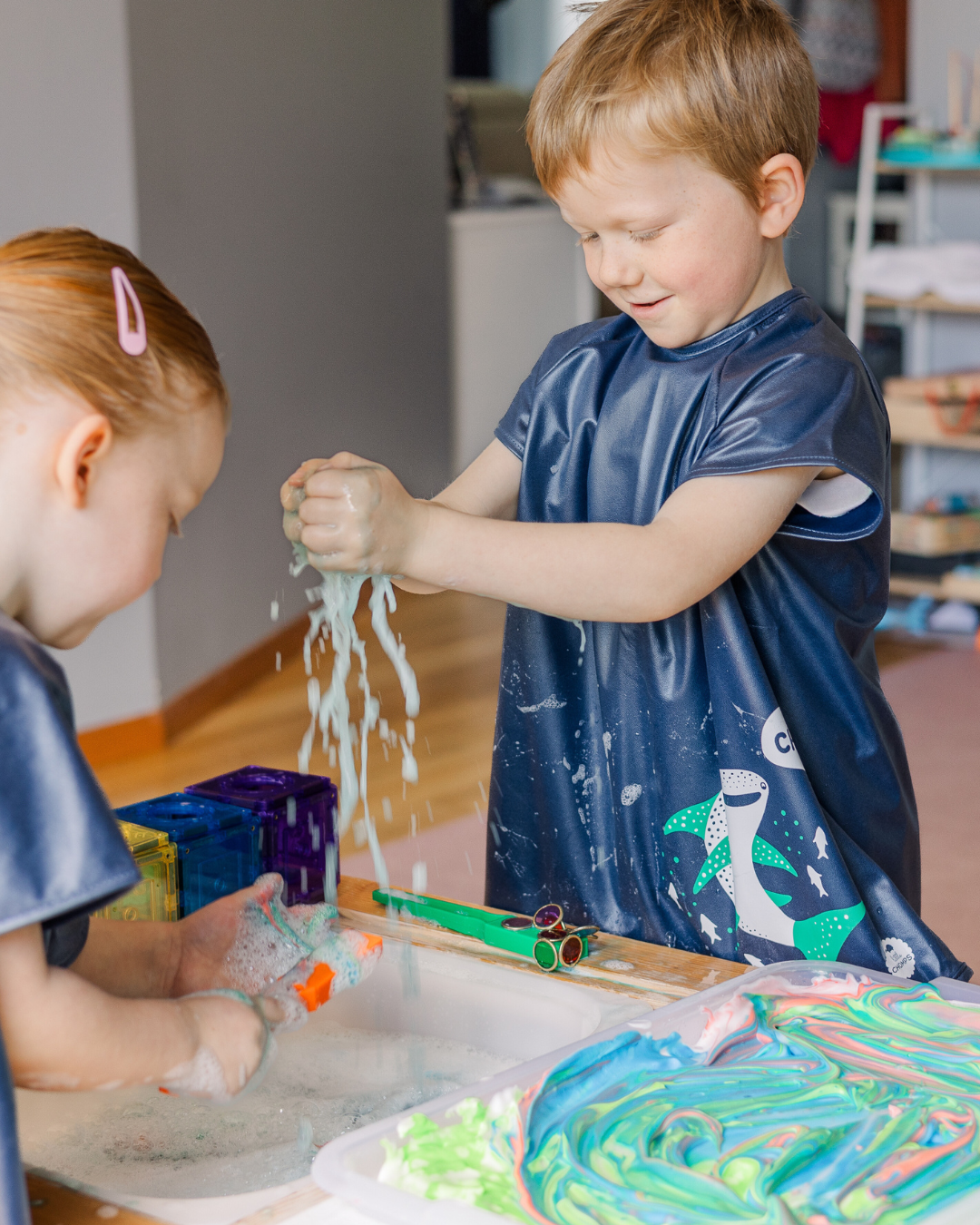 Boy and girl playing with water wearing waterproof art smocks.