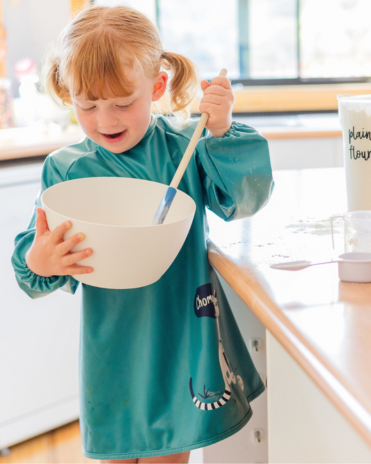 Child wearing green Preschool smock cooking.
