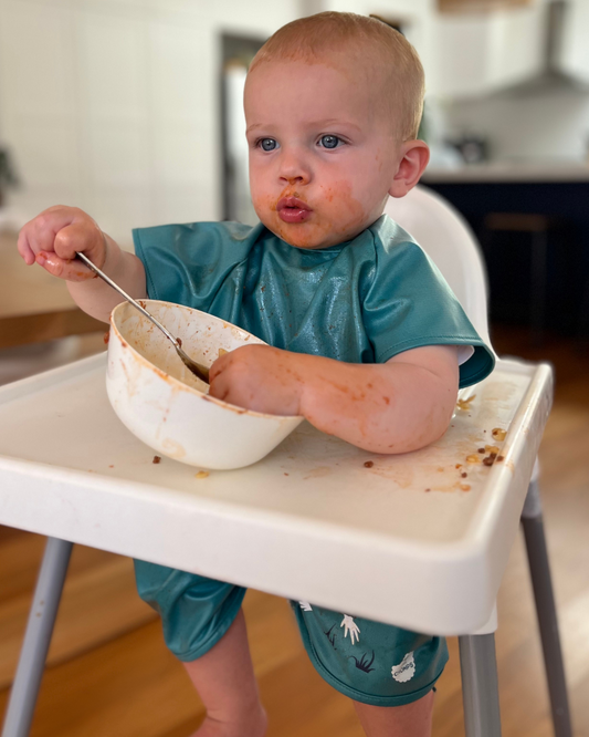 Boy wearing a short sleeved bib smock in green.